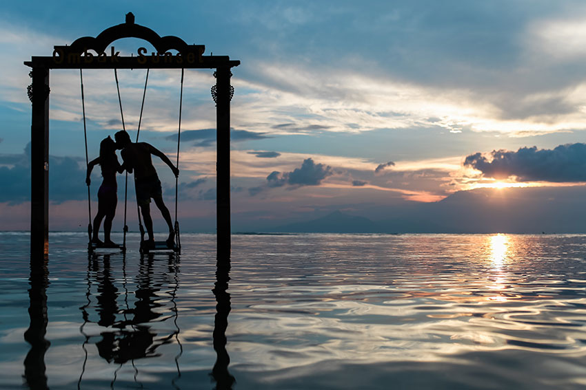 Man and woman on swing above the sea kissing