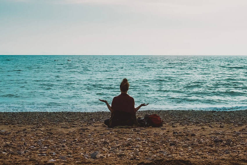 Woman sitting relaxed by the ocean meditating