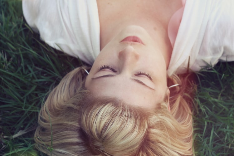 The head of a blonde woman lying in a field of grass