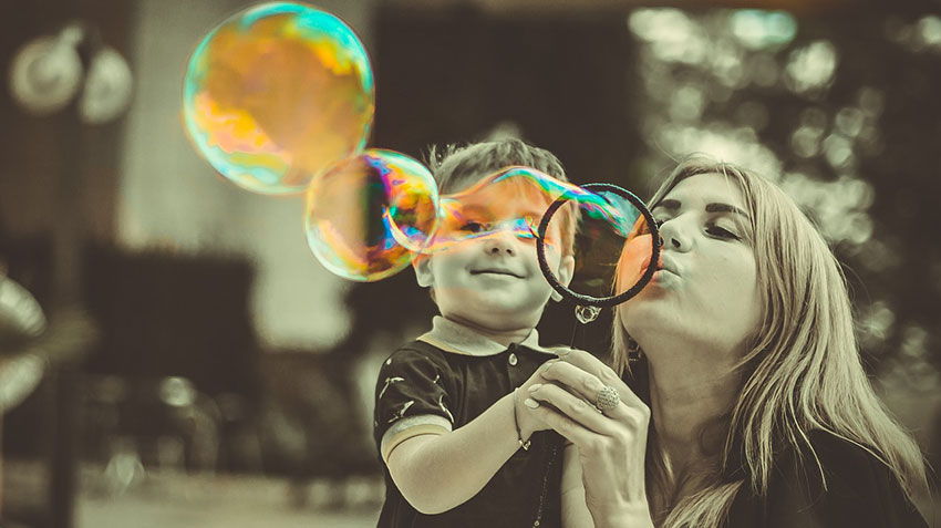 Mom and son having fun blowing rainbow bubbles