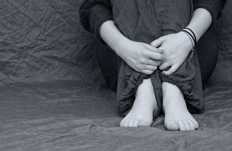 Person sitting with arms around legs black and white