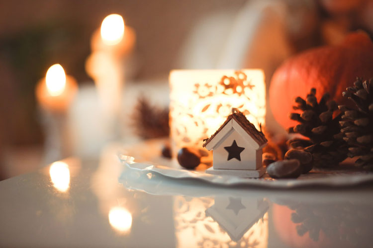 Fall and Holiday seasonal decorations with candle, pumpkin, and pinecone on a table