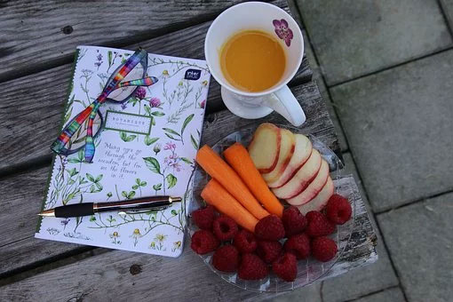 Glasses and pen with a notebook and plate of healthy food and a cup of tea