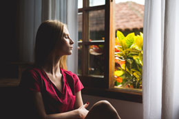 Woman closing eyes by window