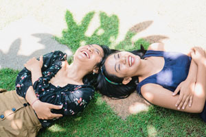 Two women laying in the grass laughing together