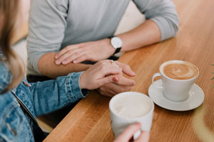 Couple drinking coffee while also holding hands