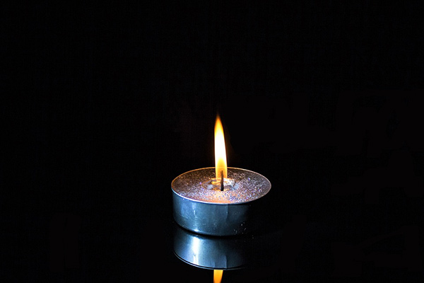 Single candle lit in a dark room.