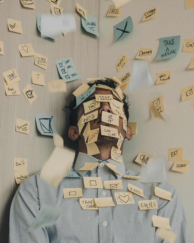 Distressed employee covered in instructional sticky notes.