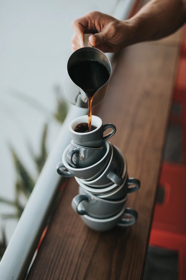 A person pouring coffee into a precariously perched mug.