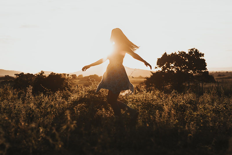 Woman dancing in a field realizing the benefits of therapy
