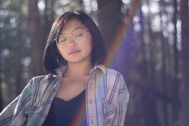 Woman closing her eyes focusing on her breath outdoors