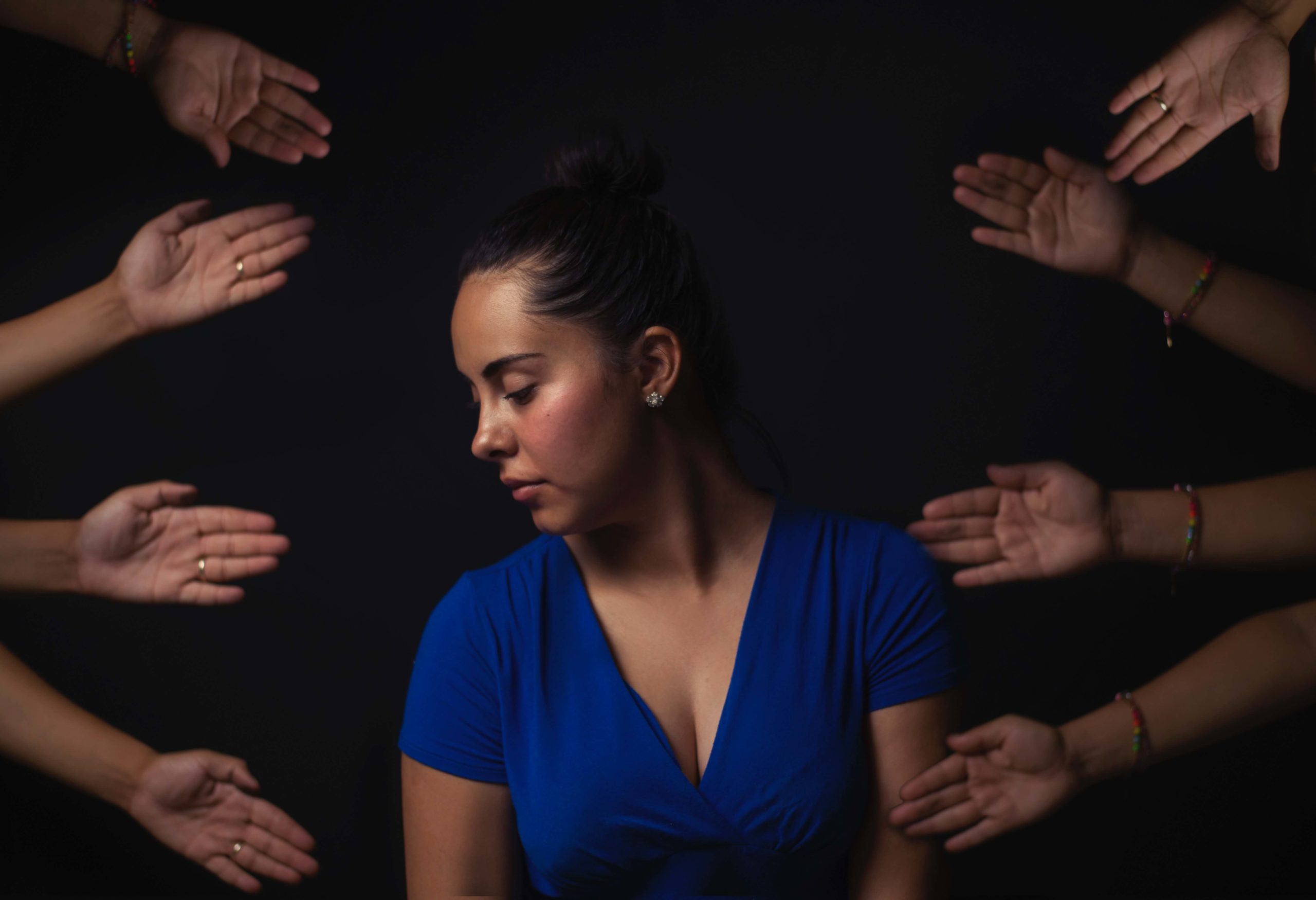 Image of a young woman surrounded by hands