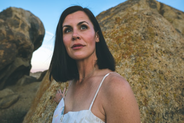 Woman looking up and hopeful outside near a rock formation