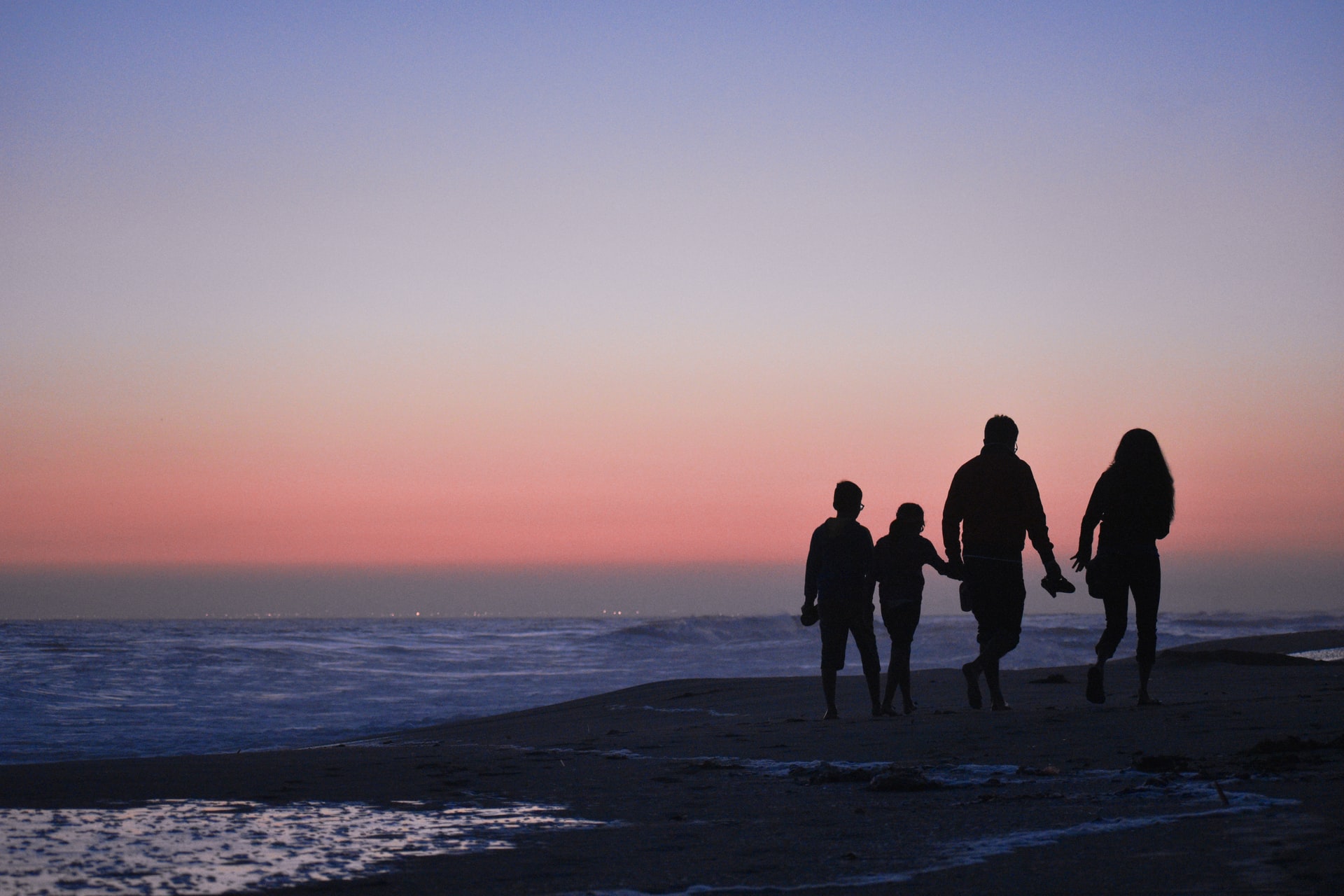 Family taking a walk at sunset on the beach