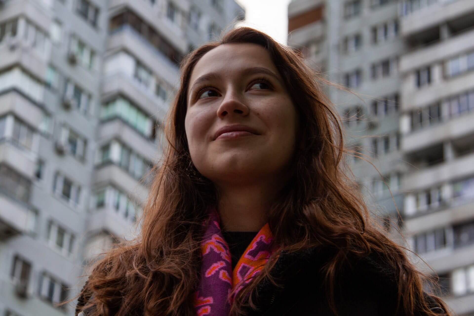 Young woman smiling and looking hopeful outside in the city