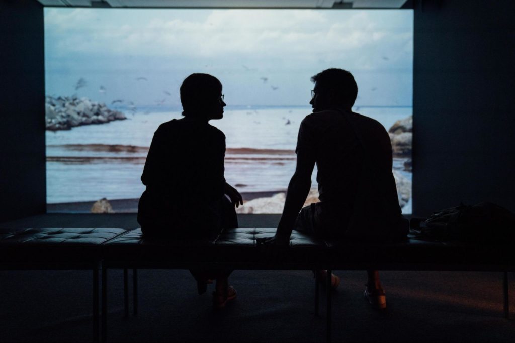 Two people speaking in front of a screen of the ocean