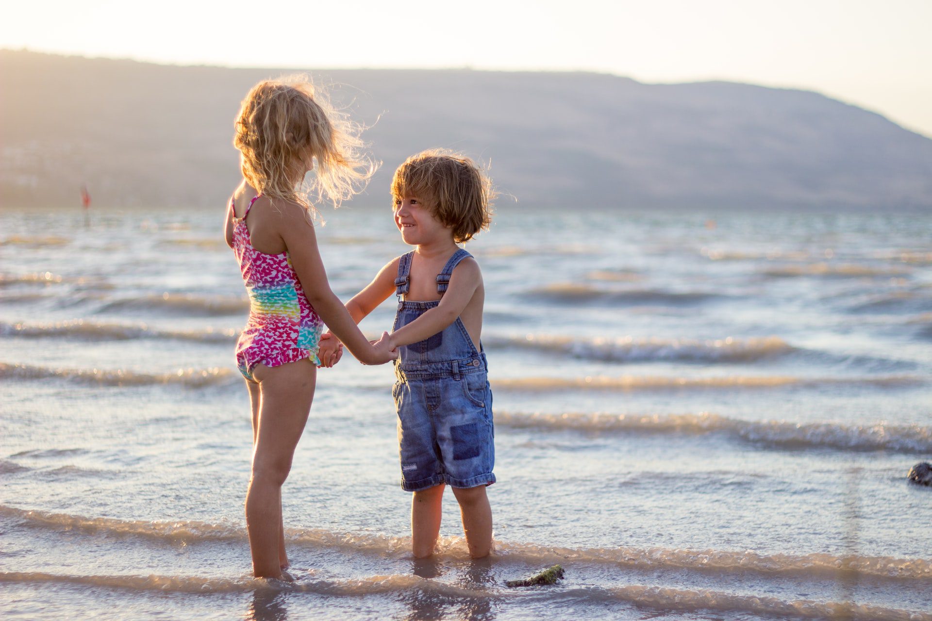Two children standing on the beach holding hands