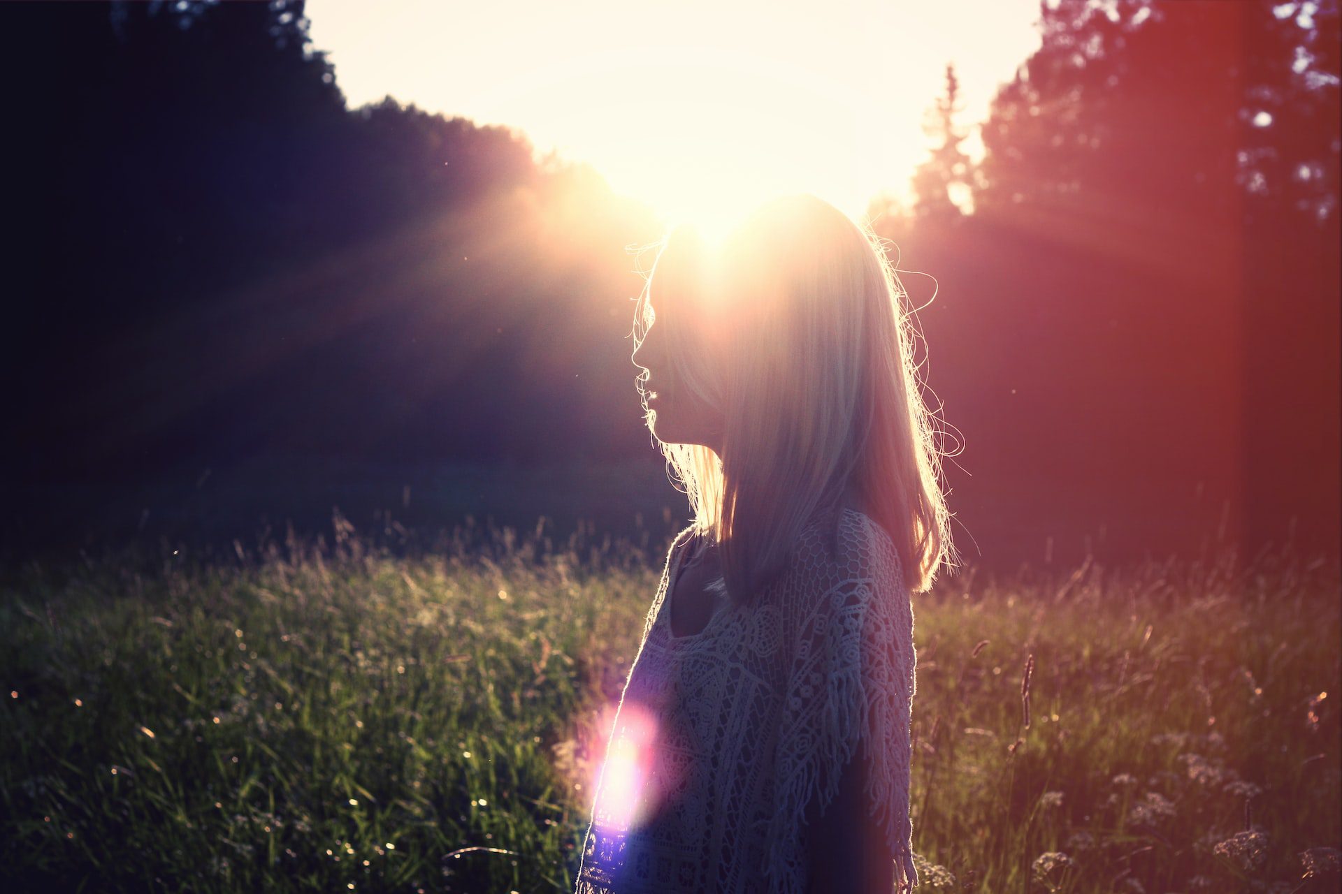 Photo of a woman in profile at sunset with the sun shining behind her
