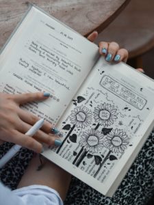 Person holding a journal with notes and flower drawings