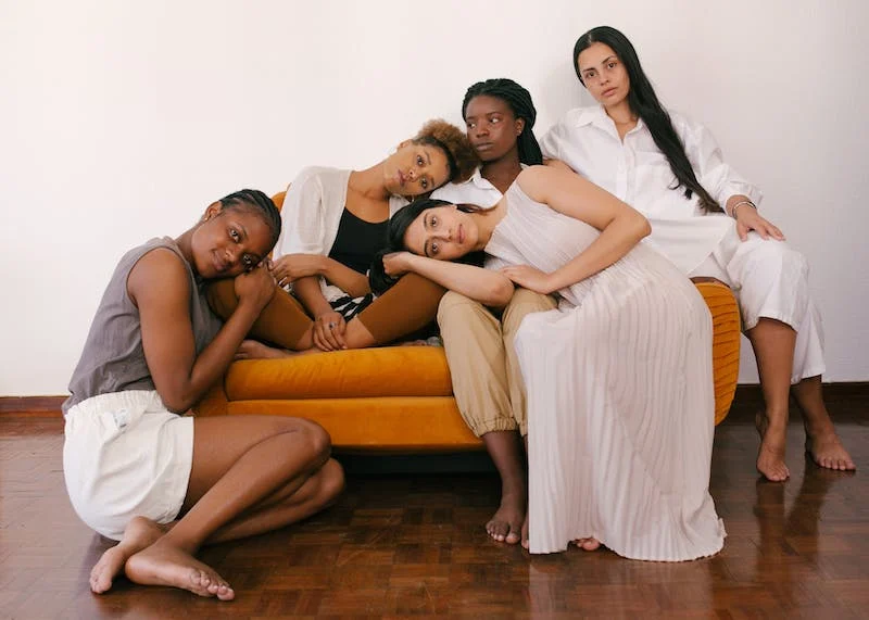 A group of women lean on each other on a couch