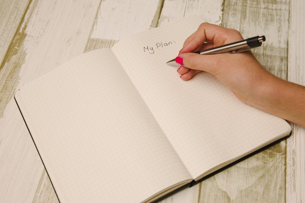 Photo of someone writing in their journal notebook and planner
