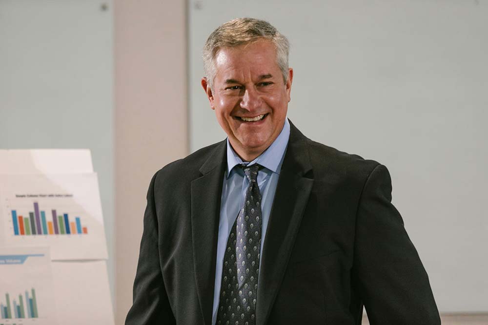 A man in a suit stands in front of a presentation after executive therapy in Miami
